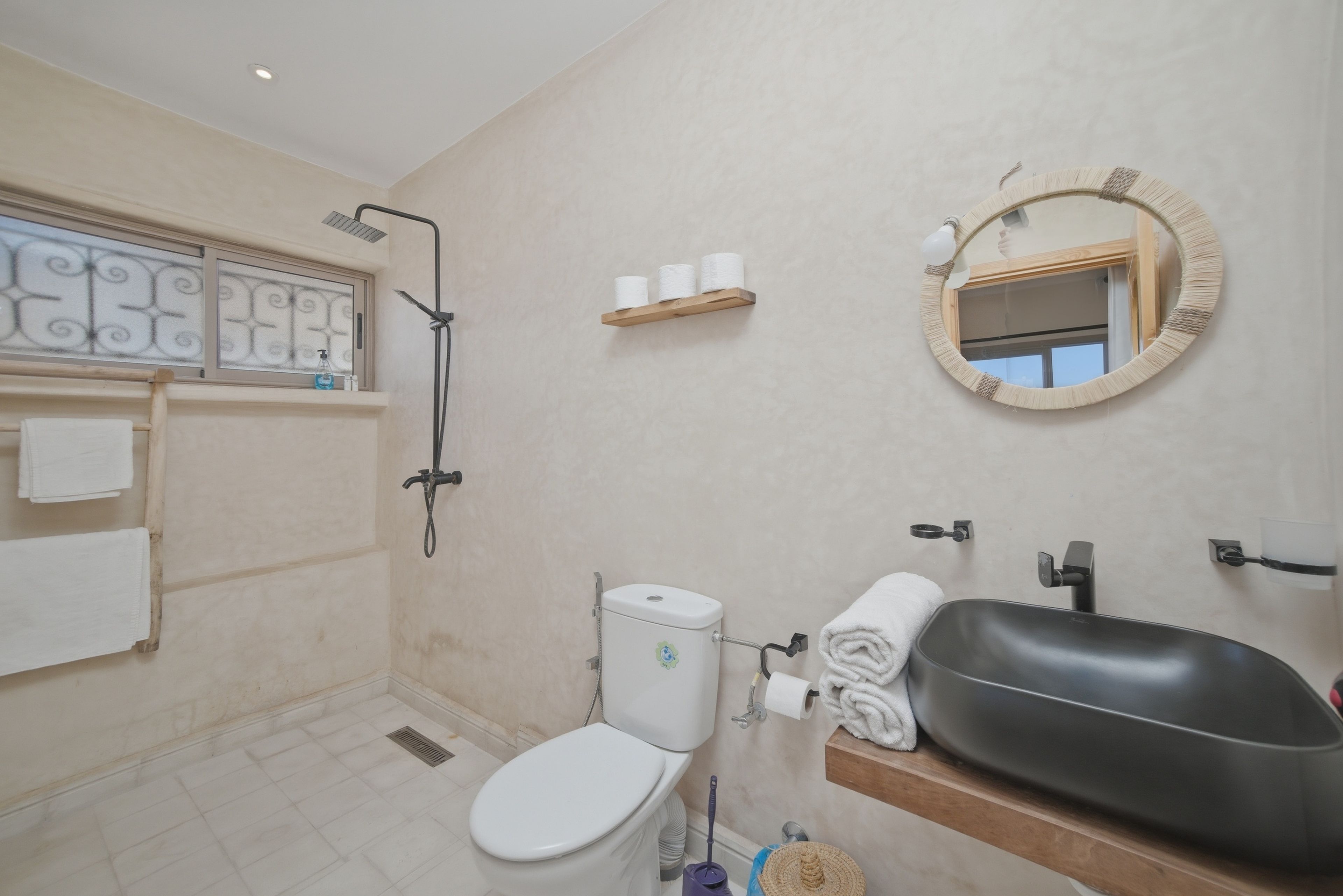 A bathroom with a toilet, bidet, sink, mirror, and towel rack.
