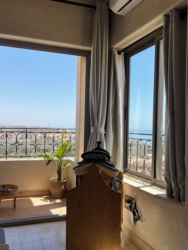 Un balcon avec vue sur la mer, une plante en pot et une structure en bois.