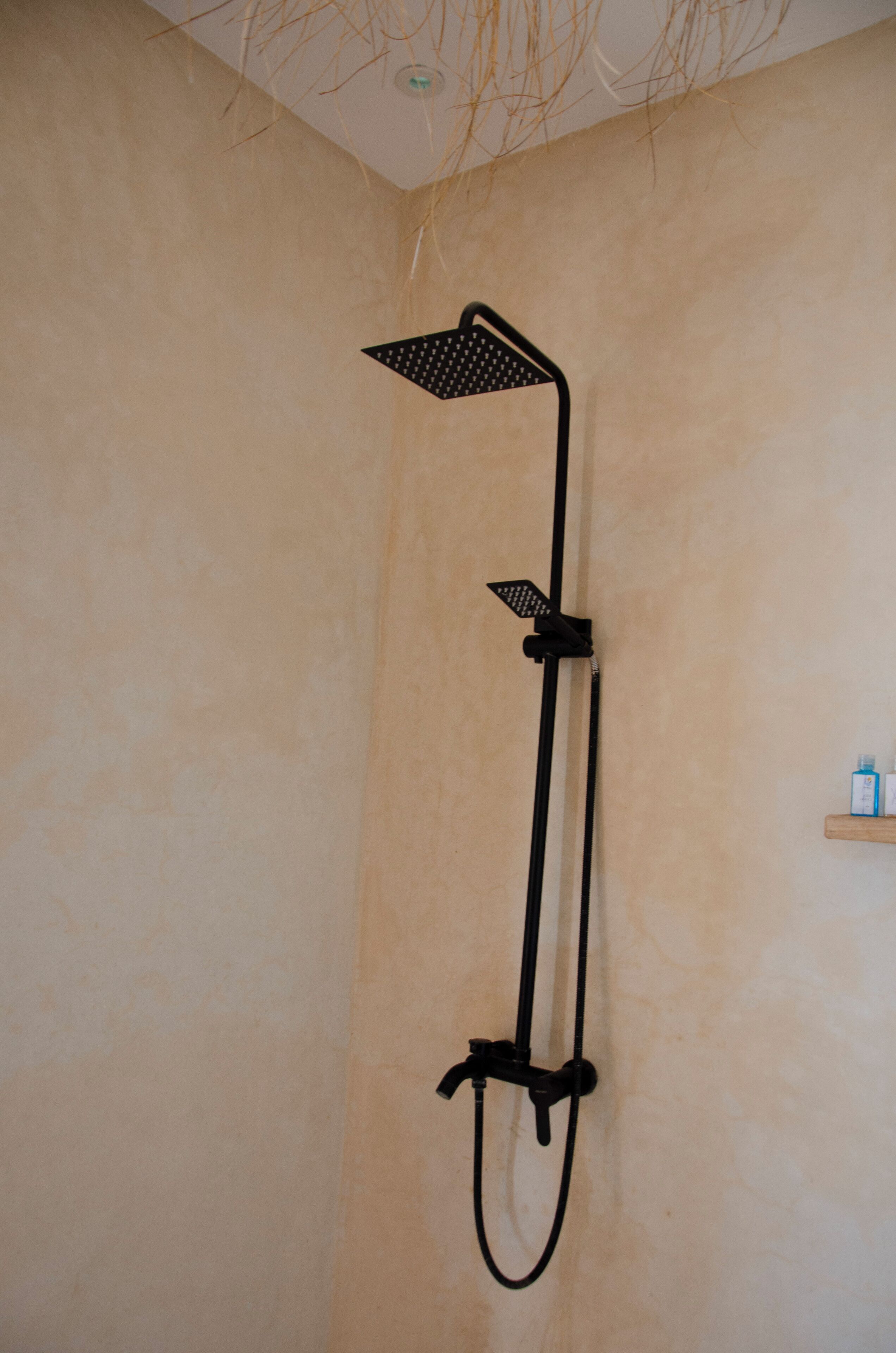 A black showerhead mounted on a beige wall.