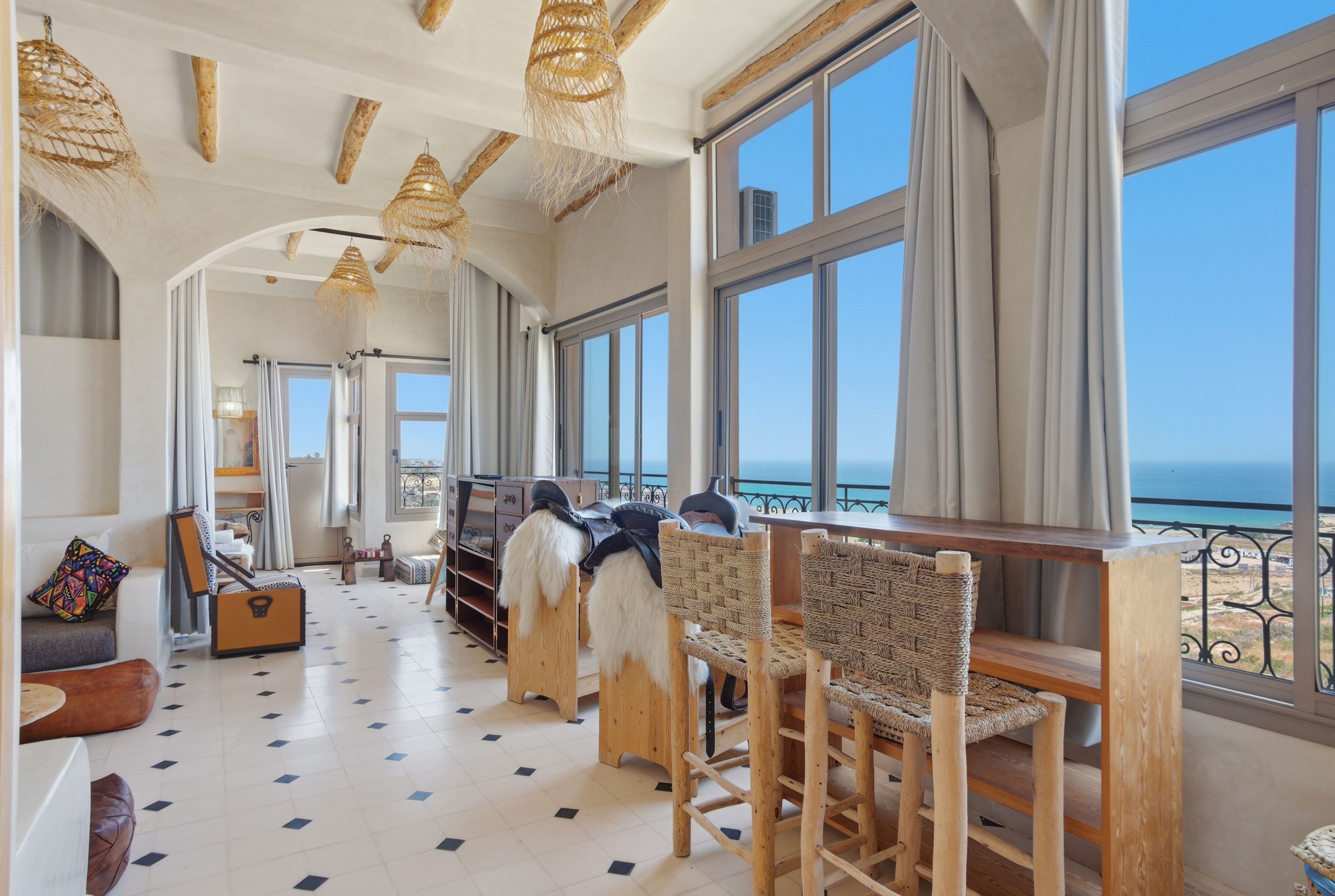 A spacious room with large windows, a wooden floor, and a view of the sea.