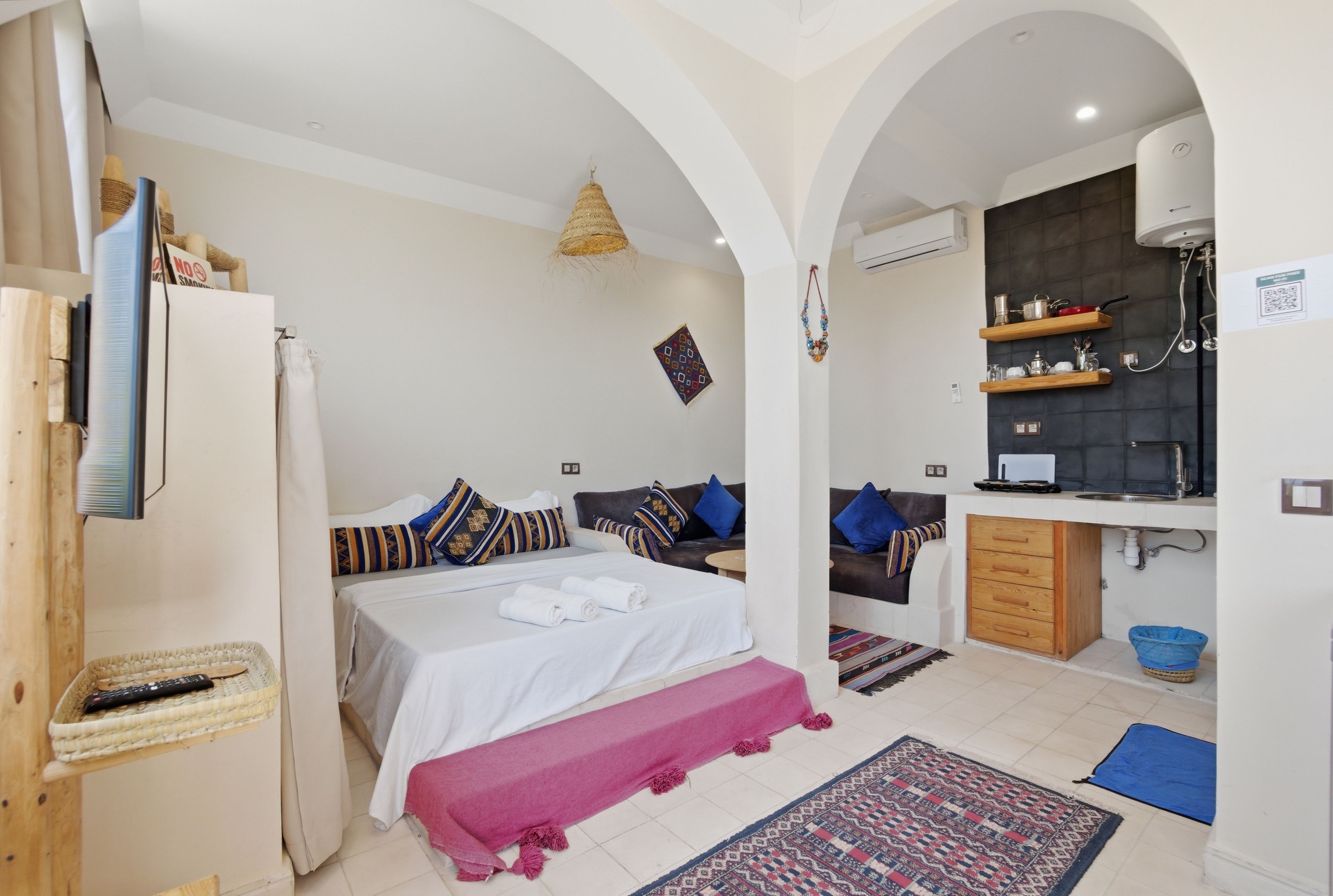 Une chambre d’hôtel comprenant un lit, une banquette, une kitchenette et une salle de bain.