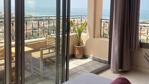 Une chambre d’hôtel avec un balcon, un lit agrémenté de serviettes roulées, une plante en pot et une vue sur la plage et l’océan.