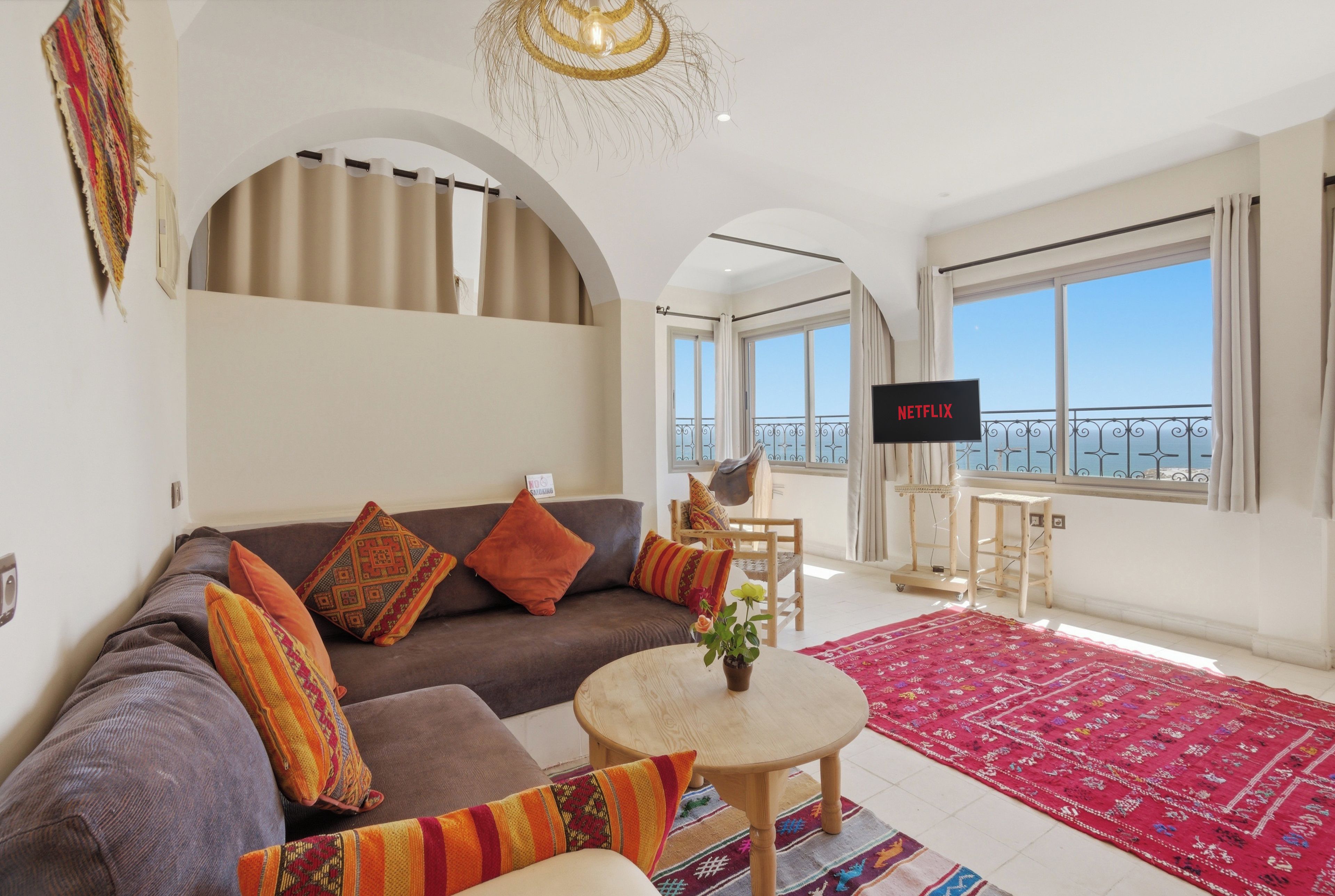 A living room with a sofa, a coffee table, a TV, and a view of the sky.
