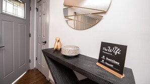 A modern hallway with a dark wooden bench, a decorative mirror, and a sign indicating free WiFi access.