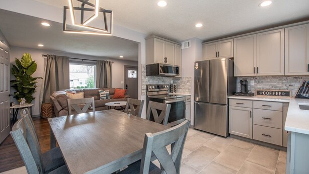 A modern kitchen with stainless steel appliances, a dining area with a wooden table and chairs, and a living area with a sofa and a coffee table.