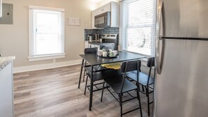 Una cocina compacta con una mesa de comedor, sillas, un refrigerador, un microondas y una estufa.