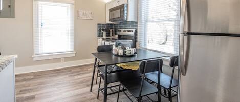 A compact kitchen with a dining table, chairs, a refrigerator, a microwave, and a stove.