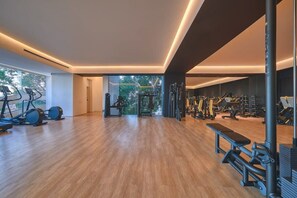 A spacious gym with cardio machines, weightlifting equipment, and benches.