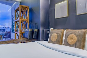 A modern hotel room with a large bed, wooden furniture, and a view of the city.
