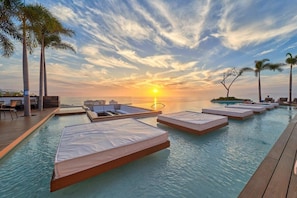 Ein Poolbereich mit Liegestühlen und Blick auf den Sonnenuntergang.