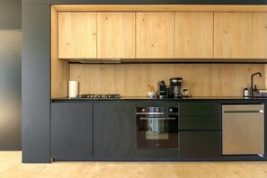 A modern kitchen with wooden cabinets, a built-in oven, a dishwasher, and a coffee maker.
