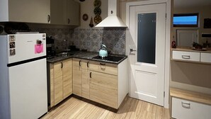 A modern kitchen with wooden cabinets, a white refrigerator, and a sink. - One bedroom flat in the center of Riga (Riga)