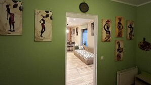A room with green walls, a bed with a patterned bedspread, and several artworks on the walls. - One bedroom flat in the center of Riga (Riga)