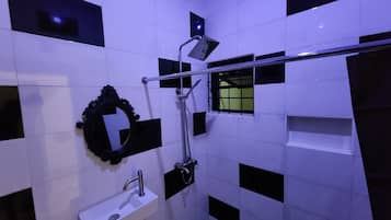Un baño con lavamanos blanco, espejo y zona de ducha.