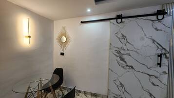 A modern interior with a marble wall, a sunburst mirror, and a minimalist seating arrangement.