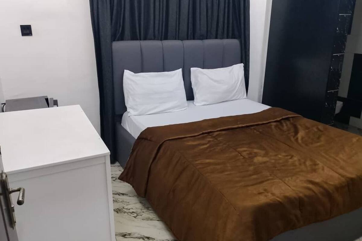 A room with a bed, a white cabinet, and a dark curtain.