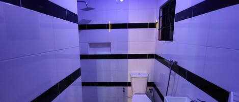 A bathroom with a toilet, sink, and shower. The walls are tiled with black and white stripes.