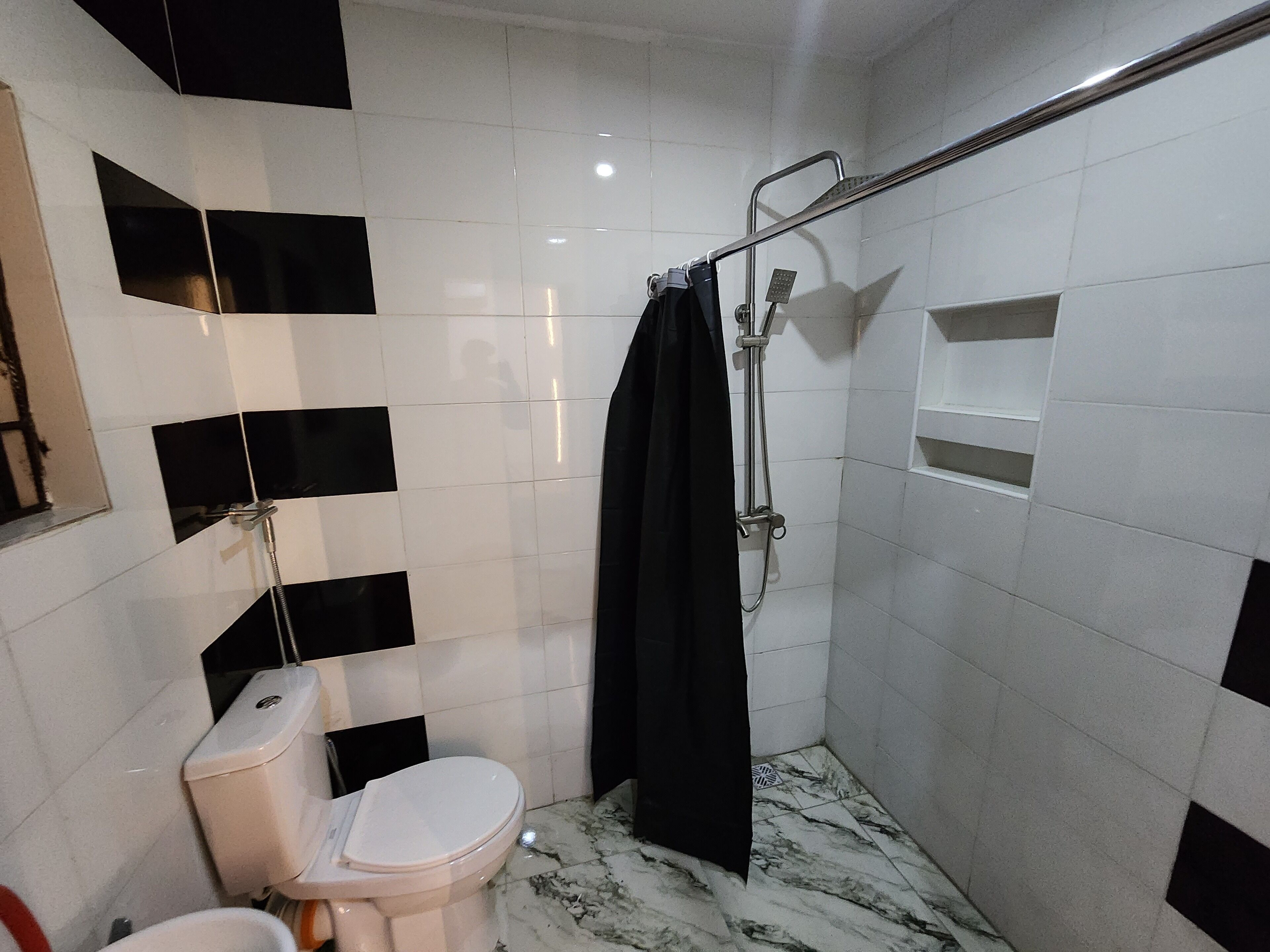 A bathroom with a toilet, a shower with a glass door, and a tiled floor.