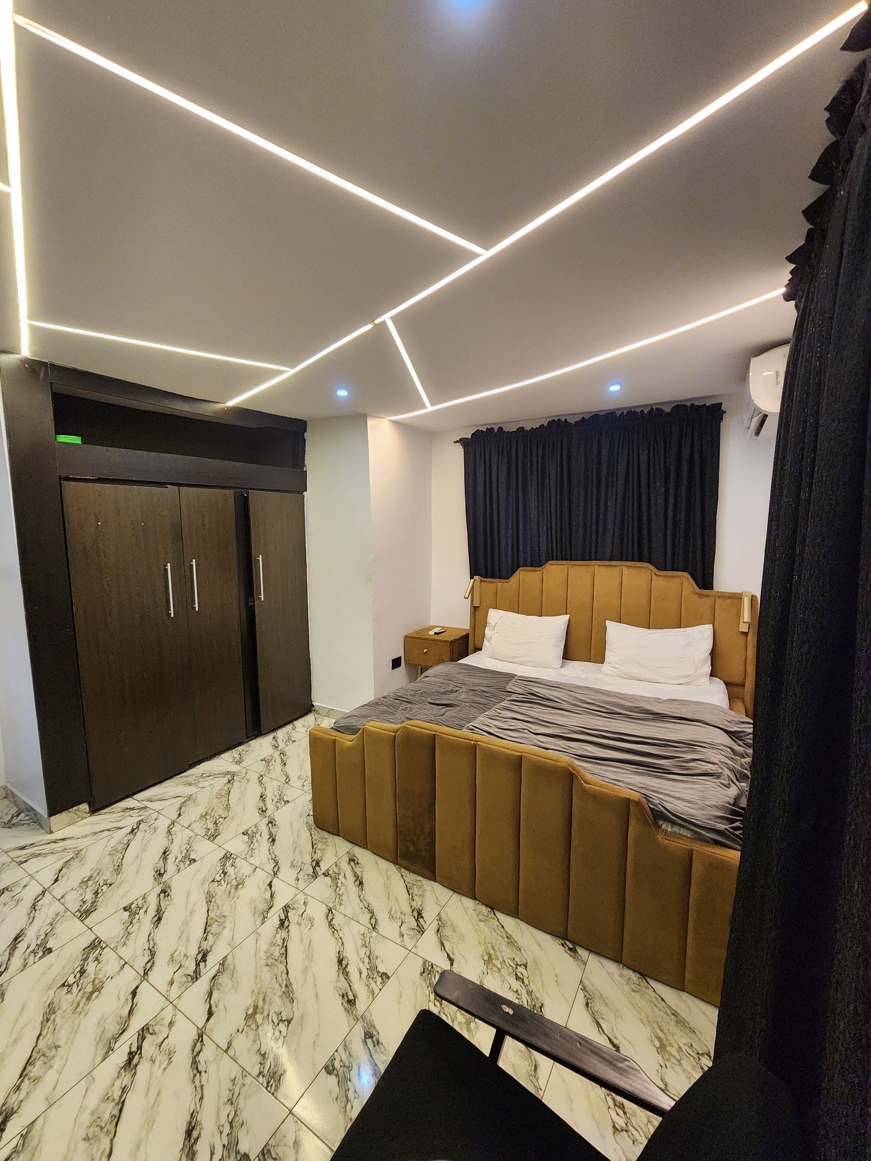 A bedroom with a bed, a wardrobe, a nightstand, and a ceiling light fixture.