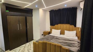 A bedroom with a bed, a wardrobe, a nightstand, and a ceiling light fixture.
