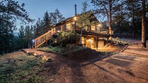 Une cabane en bois à deux étages, dotée d’une terrasse couverte et d’un escalier menant à l’étage supérieur.