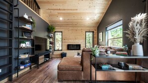 Een moderne woonkamer met een houten plafond, inbouwkasten, een leren bank en een groot raam.
