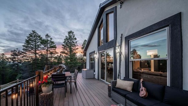 Een modern huis met een terras, buitenmeubels en een gitaar.