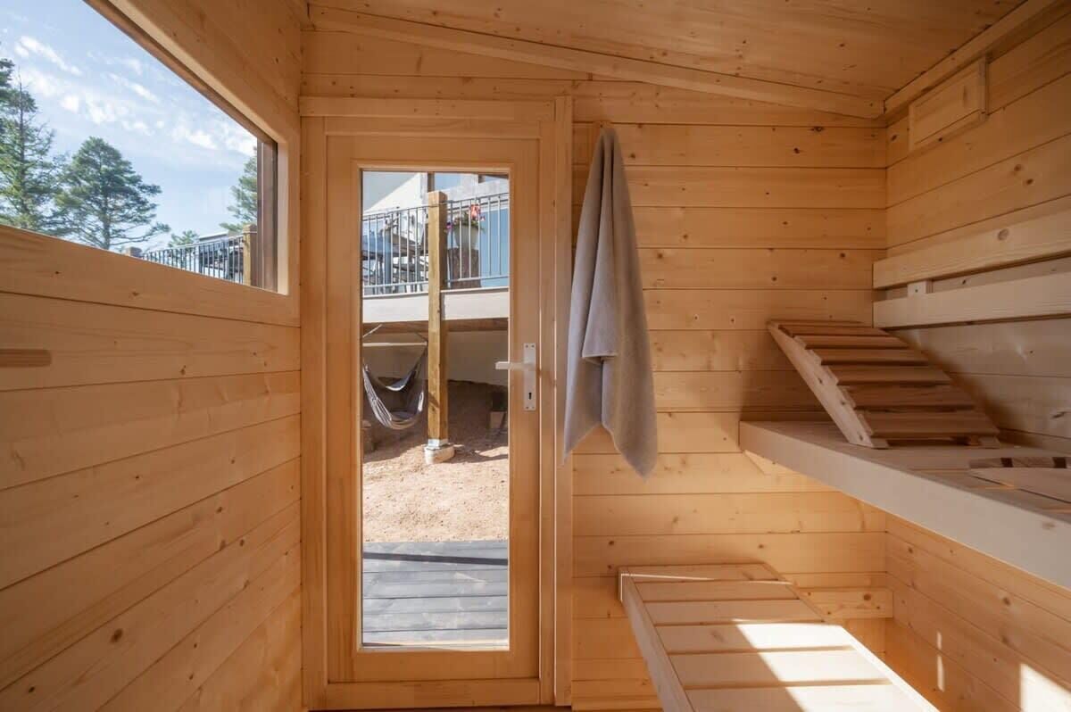 A wooden cabin with a balcony, a door leading outside, and a wooden staircase.