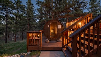 A wooden cabin with a circular interior, a deck, and a staircase leading to the entrance.