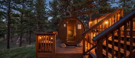 Une cabane en bois dotée d’un intérieur circulaire, d’une terrasse et d’un escalier menant à l’entrée.