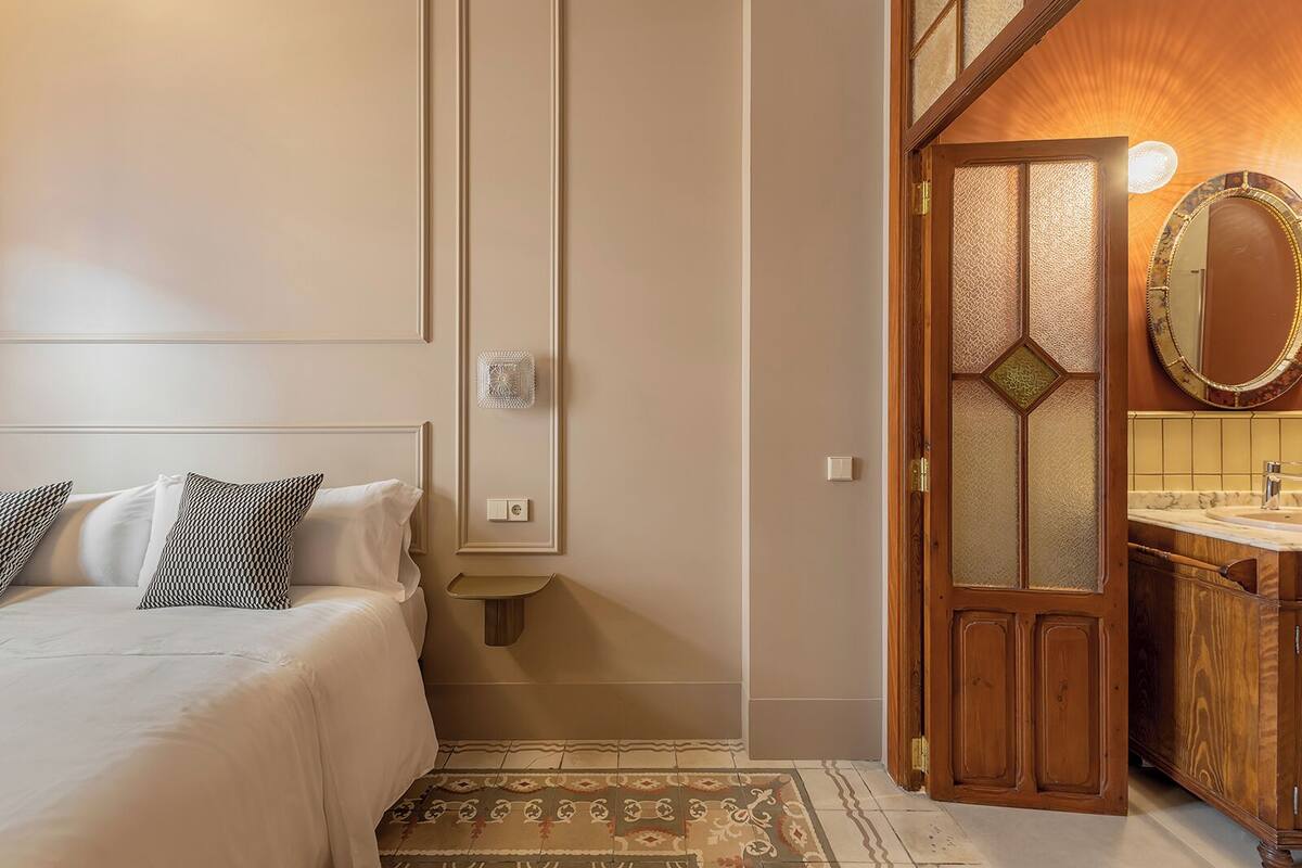 Ein Schlafzimmer mit Bett, Nachttisch und einem gemusterten Teppich.