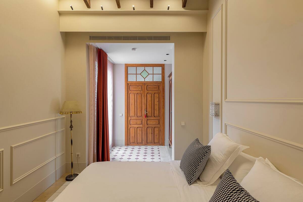 Ein Hotelzimmer mit Bett, Lampe, Tür und einem gemusterten Boden.