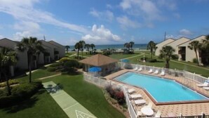 A resort with a swimming pool surrounded by lounge chairs and a small pavilion.