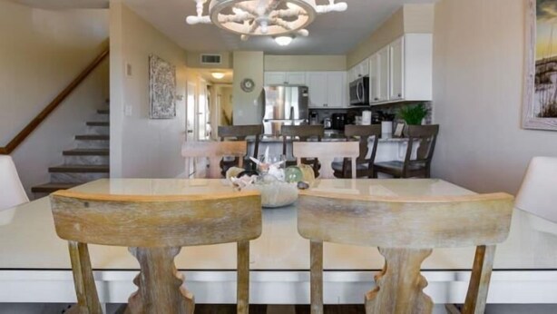 A dining area with a chandelier, white cabinets, and a staircase in the background.