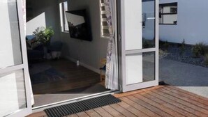 A modern house with a wooden deck, a sliding glass door, and a visible outdoor area with plants. - New, family friendly warm /3bedroom3bathroom/kingbed, mountain view/unitB (Lake Tekapo)