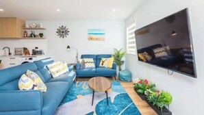A modern living room with a blue sofa, a coffee table, and a flat-screen TV mounted on the wall. - New, family friendly warm /3bedroom3bathroom/kingbed, mountain view/unitB (Lake Tekapo)