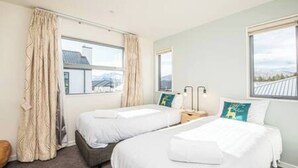 A hotel room with two single beds, a window with a view, and a bedside table with a lamp. - New, family friendly warm /3bedroom3bathroom/kingbed, mountain view/unitB (Lake Tekapo)