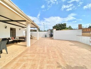 An outdoor patio area with a seating arrangement and a covered section. - Casita de La Alquería (Alhaurín de la Torre)