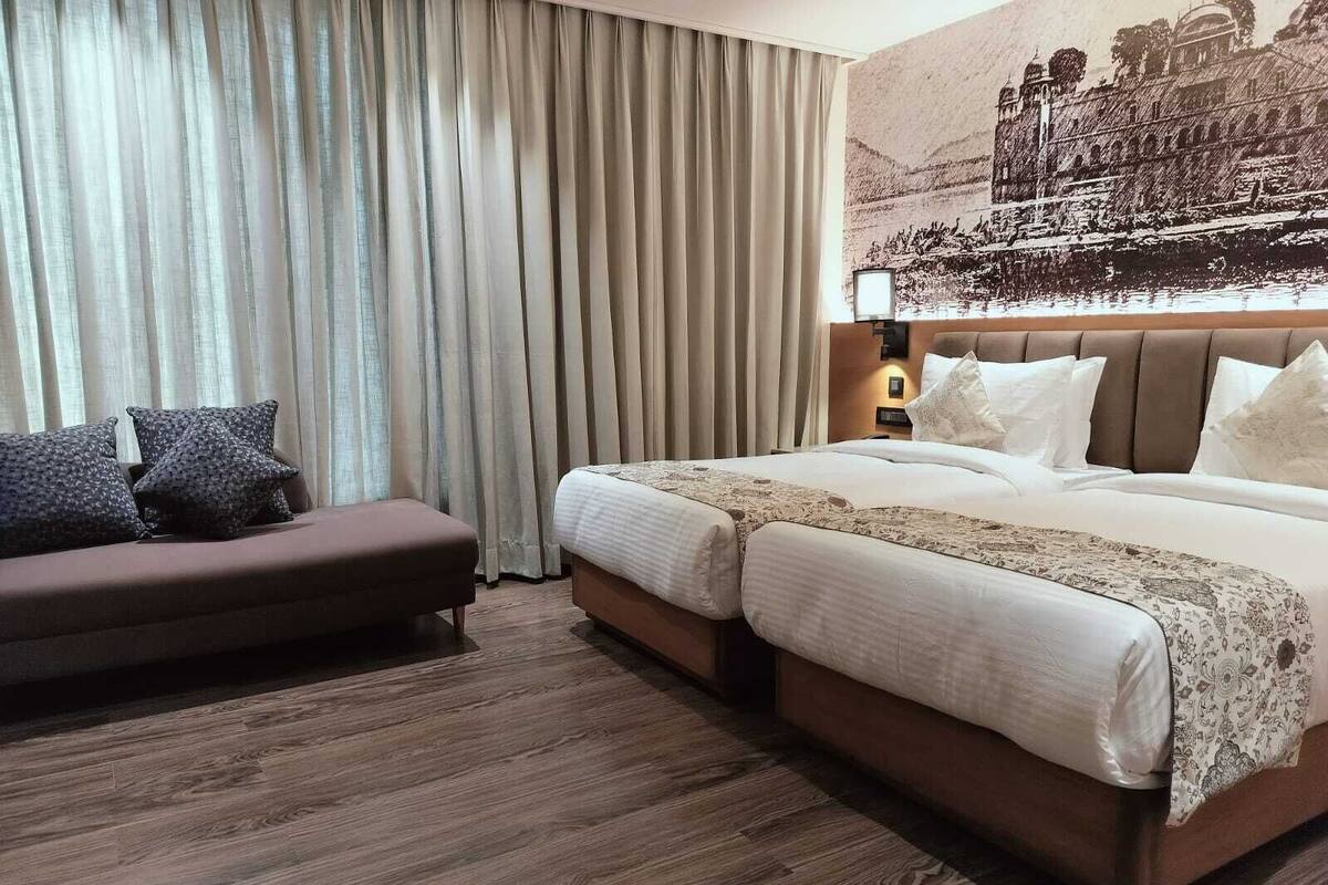 Ein Hotelzimmer mit einem großen Bett, einer Couch und einem an der Wand befestigten Fernseher.