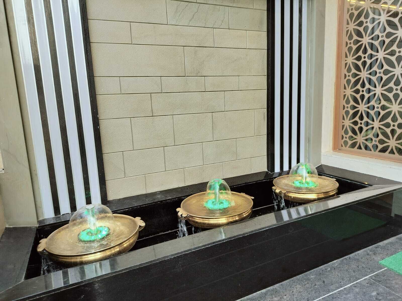 A water feature with three fountains in a modern lobby.