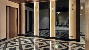 Eine moderne Hotelhalle mit geometrischem Marmorboden, Holzboden und Glastüren zu einer Sitzecke.