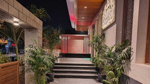 Entrada de hotel con una escalera que conduce a la recepción, rodeada de plantas en macetas y arquitectura moderna.