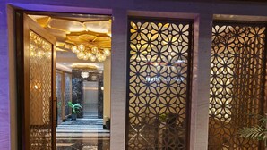 Un moderno vestíbulo de hotel con piso de mármol, paneles decorativos y un candelabro.