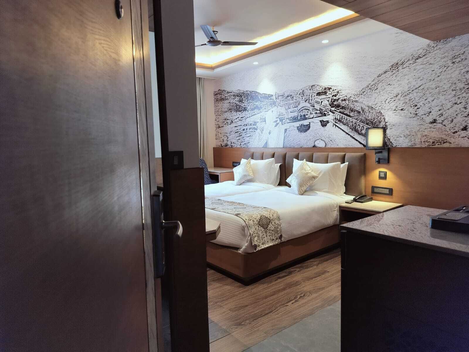 A hotel room with a large bed, a desk, and a wall-mounted TV.