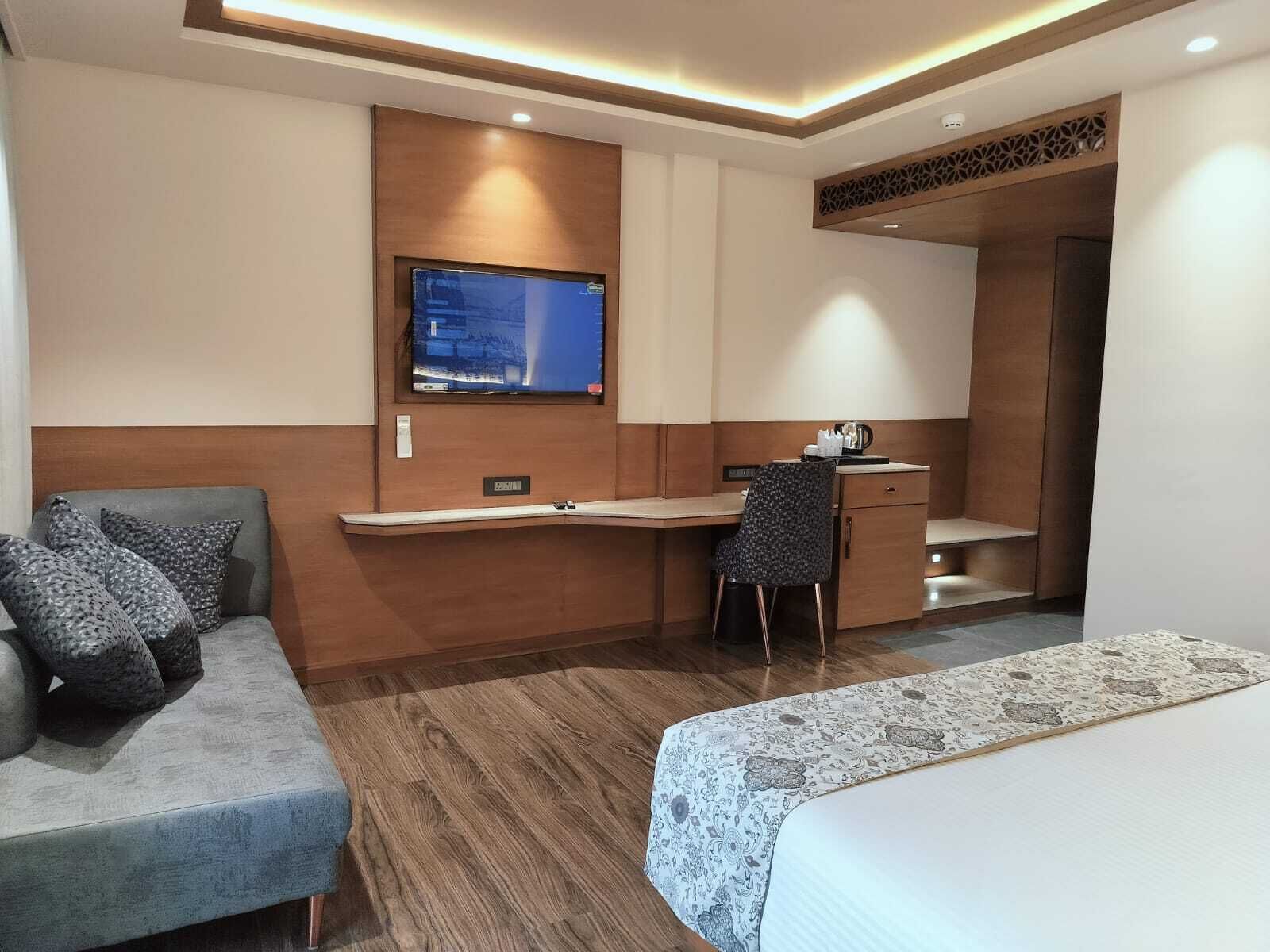 Quarto de hotel com uma cama, uma mesa, uma cadeira e uma televisão.