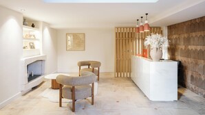 Een moderne woonkamer met dakraam, een openhaard, een houten roomdivider en een receptiebalie met een bloevas.