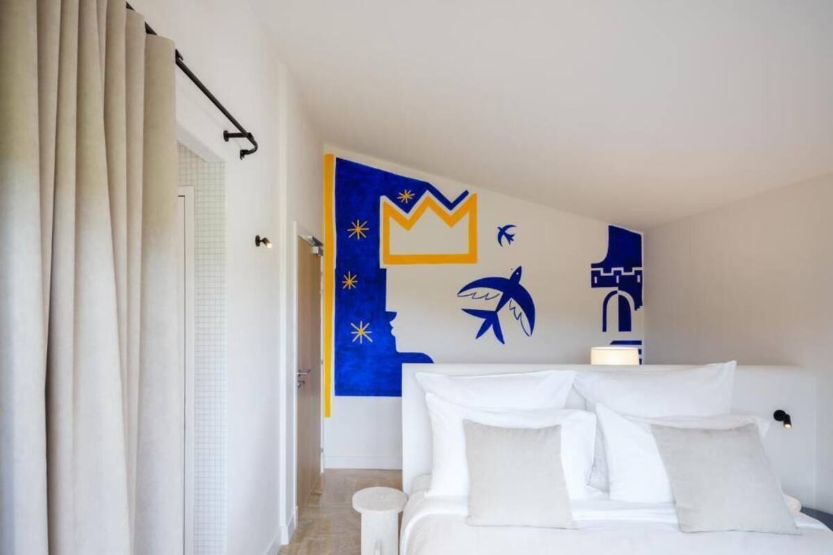 Ein Hotelzimmer mit einem Bett, einem Nachttisch und einer Wand mit abstrakter Kunst.