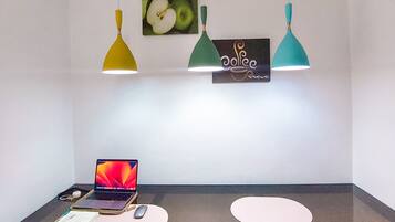 A modern dining area with a dark table, three pendant lights, and a laptop on the table.