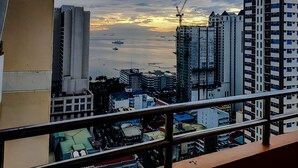 A cityscape with high-rise buildings, a construction crane, and a sunset over the water. - Birch Tower Manila (Manila)