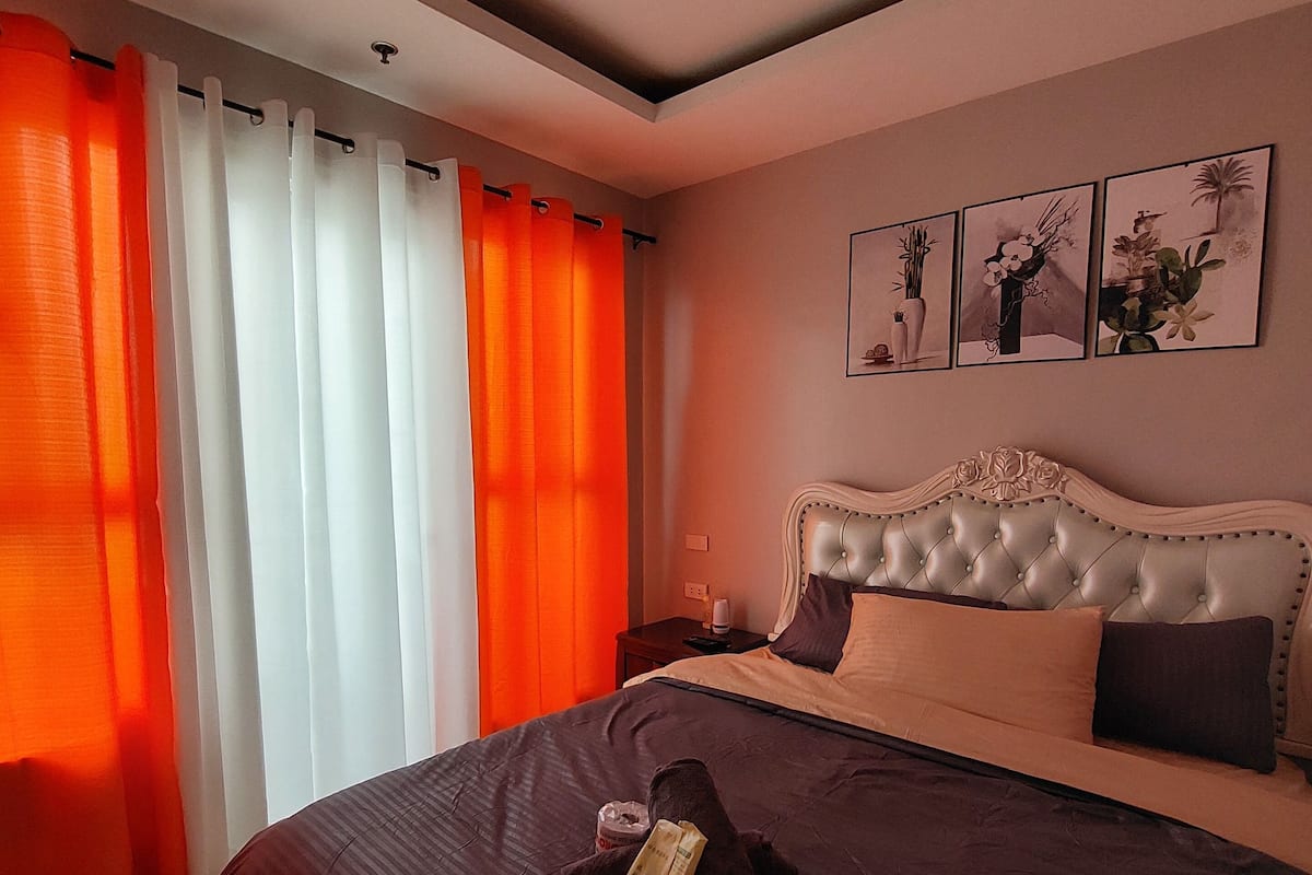 Une chambre d’hôtel avec un grand lit, une tête de lit à motifs capitonnés et trois tableaux encadrés accrochés au mur.